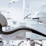 A modern dental clinic interior showcasing a dental chair and equipment in a clean, clinical setting.